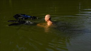 Schmitt puts his diving wet suit on in the water.